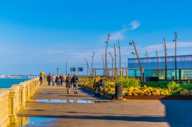 İnsanlar Cadiz 'de deniz kenarında yürüyorlar.