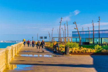 people are walking on a seaside promenade in cadiz