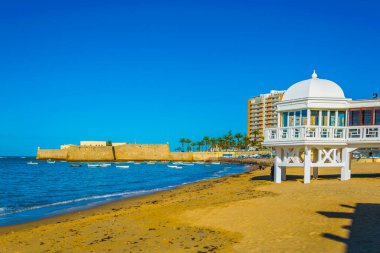 İspanya 'nın Cadiz şehrinde eski bir hamamın beyaz binalı La Caleta plajı manzarası