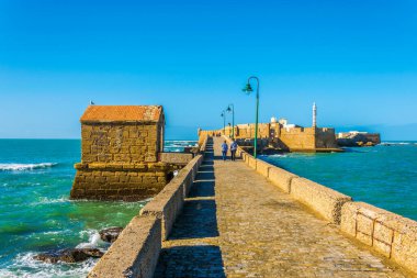 İnsanlar İspanya 'nın Cadiz kentindeki San Sebastian şatosuna giden dar bir tuğla yoldan geçiyorlar.