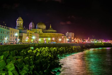 night view of the illuminated waterfront in cadiz with its majestic cathedral