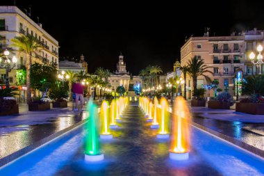 night view of a fountain situated on the square of saint john of god in cadiz with town hall on background