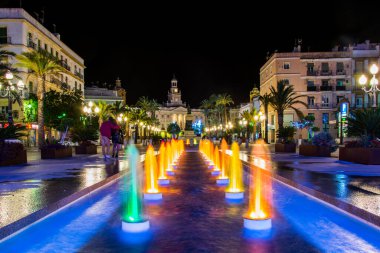 night view of a fountain situated on the square of saint john of god in cadiz with town hall on background