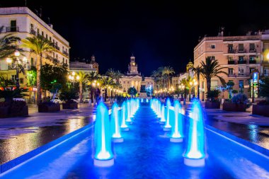 night view of a fountain situated on the square of saint john of god in cadiz with town hall on background