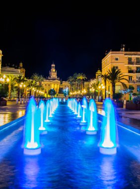night view of a fountain situated on the square of saint john of god in cadiz with town hall on background