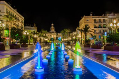 night view of a fountain situated on the square of saint john of god in cadiz with town hall on background