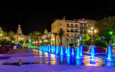 night view of a fountain situated on the square of saint john of god in cadiz with town hall on background