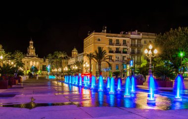 night view of a fountain situated on the square of saint john of god in cadiz with town hall on background