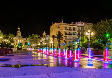 night view of a fountain situated on the square of saint john of god in cadiz with town hall on background