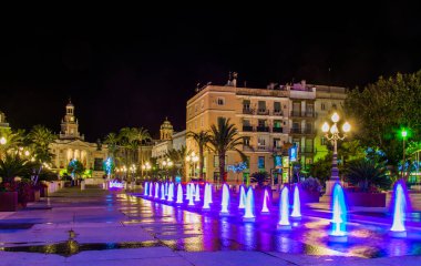 night view of a fountain situated on the square of saint john of god in cadiz with town hall on background