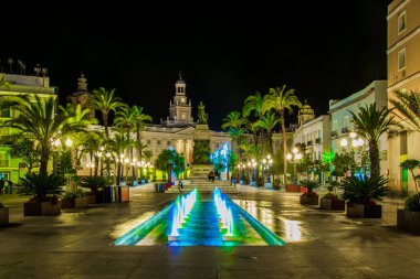 night view of a fountain situated on the square of saint john of god in cadiz with town hall on background