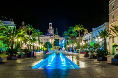 night view of a fountain situated on the square of saint john of god in cadiz with town hall on background