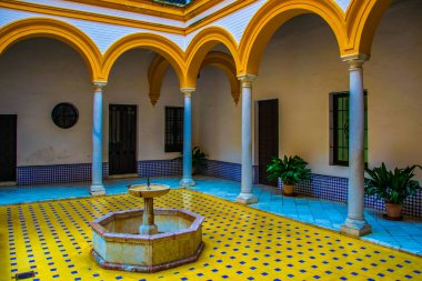 İspanyol kenti Sevilla 'daki kraliyet alcazar sarayında sarı ve beyaz fayanslarla süslenmiş küçük bir fıskiyeli avlu manzarası.