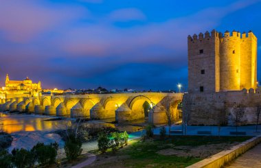 İspanyol şehri Cordoba 'daki La mezquita katedrali ve kalahorra kulesiyle Guadalquivir nehri üzerindeki aydınlatılmış Roma köprüsünün gece görüşü.