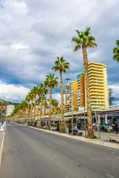 İspanya 'nın Malaga limanındaki marinayla çevrili bir gezinti güvertesinde insanlar yürüyorlar..