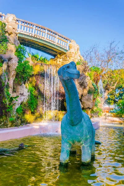 Άγαλμα Ενός Δεινοσαύρου Μπροστά Από Ένα Τεχνητό Βράχο Στο Πάρκο — Φωτογραφία Αρχείου