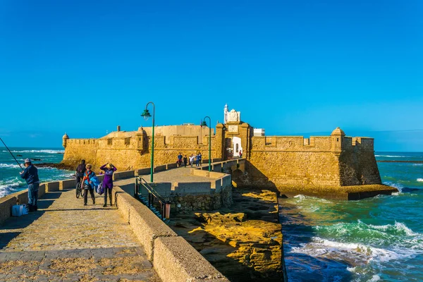 İnsanlar İspanya 'nın Cadiz kentindeki San Sebastian şatosuna giden dar bir tuğla yoldan geçiyorlar.