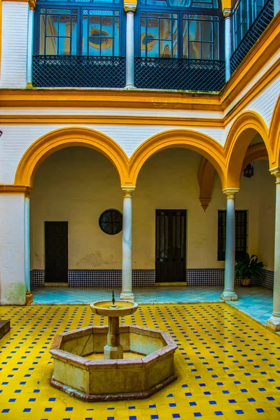 İspanyol kenti Sevilla 'daki kraliyet alcazar sarayında sarı ve beyaz fayanslarla süslenmiş küçük bir fıskiyeli avlu manzarası.