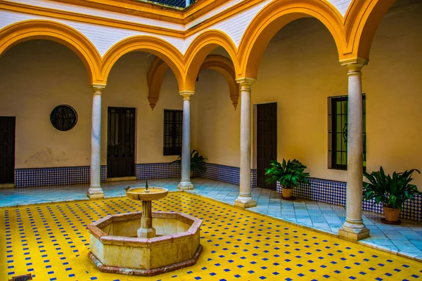 İspanyol kenti Sevilla 'daki kraliyet alcazar sarayında sarı ve beyaz fayanslarla süslenmiş küçük bir fıskiyeli avlu manzarası.