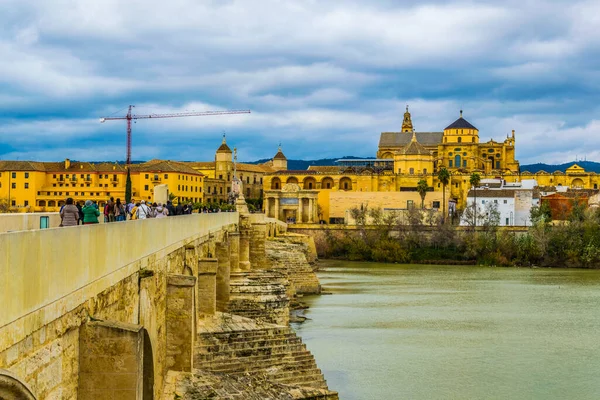 İnsanlar İspanya 'nın Cordoba şehrindeki Roma köprüsünden geçerek La mezquita katedraline doğru yürüyorlar..