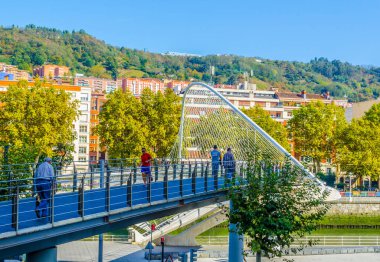 İnsanlar Bilbao, Spai 'deki Zubizuri köprüsünden geçiyorlar.