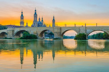 Zaragoza, Spai 'deki Basilica de nuestra senora de pilar ve puente de piedra' nın günbatımı manzarası.