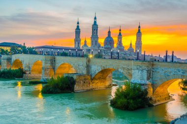 Zaragoza, Spai 'deki Basilica de nuestra senora de pilar ve puente de piedra' nın günbatımı manzarası.