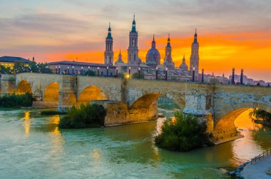 Zaragoza, Spai 'deki Basilica de nuestra senora de pilar ve puente de piedra' nın günbatımı manzarası.