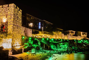 Şehri Karadeniz 'den ayıran antik duvarların egemen olduğu aydınlık eski Bulgar şehri Sozopol' un gece manzarası..