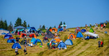 Birçok insan çadırlarıyla birlikte Chepelare yakınlarındaki dik bir tepede, Bulgaria 'daki ünlü rozhen folklor festivalinde kamp kuruyor..
