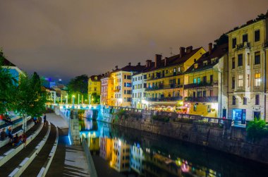 Ljubljanica nehrinin gece manzarası ve Sloven başkenti Ljubljana 'nın merkezindeki bitişik nehir kenarı.