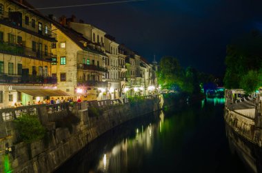 Ljubljanica nehrinin gece manzarası ve Sloven başkenti Ljubljana 'nın merkezindeki bitişik nehir kenarı.