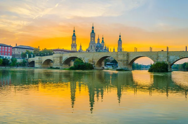 Zaragoza, Spai 'deki Basilica de nuestra senora de pilar ve puente de piedra' nın günbatımı manzarası.