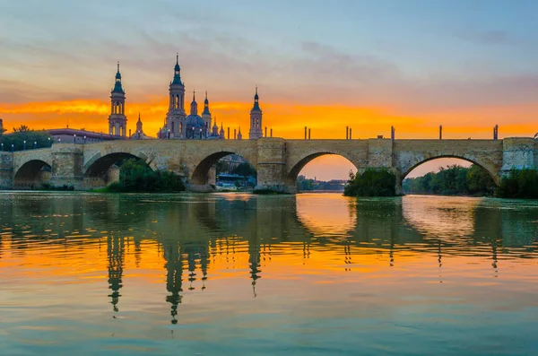 Zaragoza, Spai 'deki Basilica de nuestra senora de pilar ve puente de piedra' nın günbatımı manzarası.