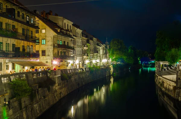 Ljubljanica nehrinin gece manzarası ve Sloven başkenti Ljubljana 'nın merkezindeki bitişik nehir kenarı.