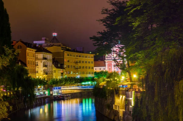 Üçlü köprüsü olan Ljubljanica nehrinin gece manzarası ve Sloven başkenti Ljubljana 'daki Fransisken kilisesi.