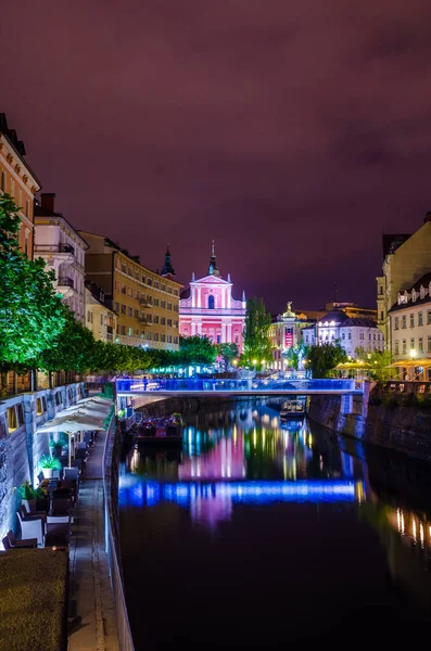 Üçlü köprüsü olan Ljubljanica nehrinin gece manzarası ve Sloven başkenti Ljubljana 'daki Fransisken kilisesi.