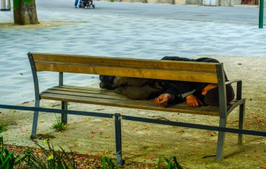 Homeless person is sleeping on a bench in the center of vienna, austria.