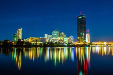 View of the UNO city complex including VIC,UN headquarters and a riverside promenade full of bars and restaurants during night in Vienna, Austria.