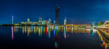 Avusturya 'nın Viyana kentinde Donauturm, VIC, BM karargahı ve gece boyunca barlar ve restoranlarla dolu bir nehir kenarı kompleksi manzarası.