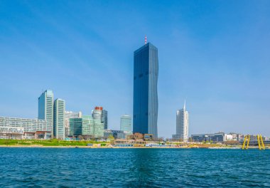 VİC, BM karargahı ve Avusturya 'nın Viyana kentinde bar ve restoranlarla dolu nehir kenarındaki bir gezinti alanı da dahil olmak üzere UNO şehir kompleksinin manzarası.