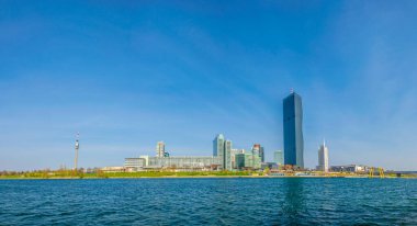 VİC, BM karargahı ve Avusturya 'nın Viyana kentinde bar ve restoranlarla dolu nehir kenarındaki bir gezinti alanı da dahil olmak üzere UNO şehir kompleksinin manzarası.