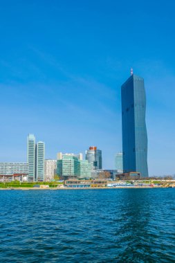 VİC, BM karargahı ve Avusturya 'nın Viyana kentinde bar ve restoranlarla dolu nehir kenarındaki bir gezinti alanı da dahil olmak üzere UNO şehir kompleksinin manzarası.