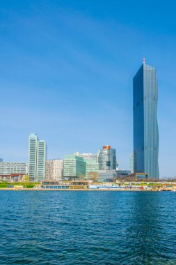 VİC, BM karargahı ve Avusturya 'nın Viyana kentinde bar ve restoranlarla dolu nehir kenarındaki bir gezinti alanı da dahil olmak üzere UNO şehir kompleksinin manzarası.