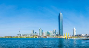 VİC, BM karargahı ve Avusturya 'nın Viyana kentinde bar ve restoranlarla dolu nehir kenarındaki bir gezinti alanı da dahil olmak üzere UNO şehir kompleksinin manzarası.