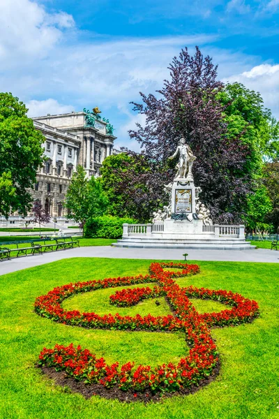 有名な作曲家ヴォルフガング アマデウス モーツァルトの像で ブルガルテン ウィーン オーストリアに花の装飾が施されています — ストック写真