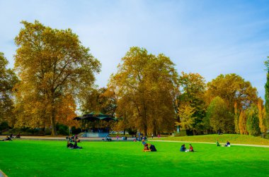 İnsanlar Central Zuric 'teki Platzspitz parkında çimlerde dinleniyorlar.