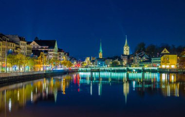 Zürih 'teki limmat nehrinin gece manzarası. Sahtekarlığın görkemli kuleleri, grossmunster kilisesi ve arka planda Aziz Paul kilisesi.