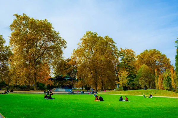 İnsanlar Central Zuric 'teki Platzspitz parkında çimlerde dinleniyorlar.