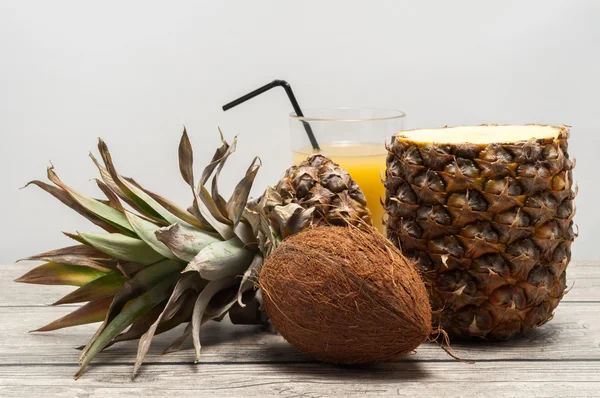 Kokos a napůl řez ananas na dřevěné desce — Stock fotografie